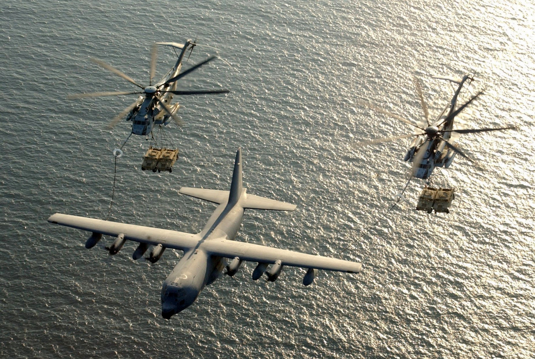 CH-53 Super Stallion helicopters receiving fuel from KC-130 Hercules over water