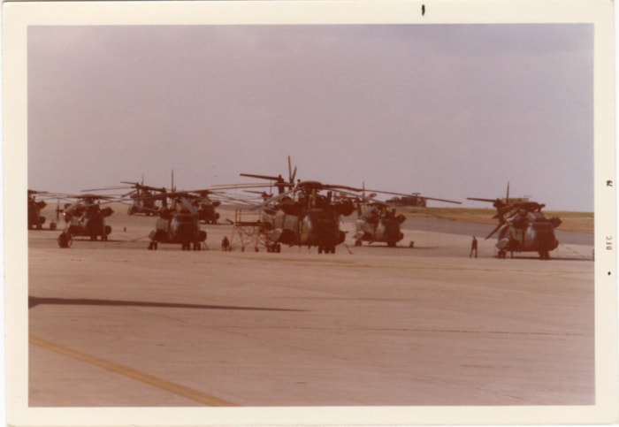 Row of military helicopters parked on tarmac