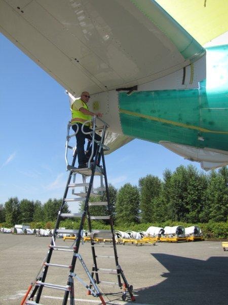 Technician on Little Giant ladder performing aircraft maintenance