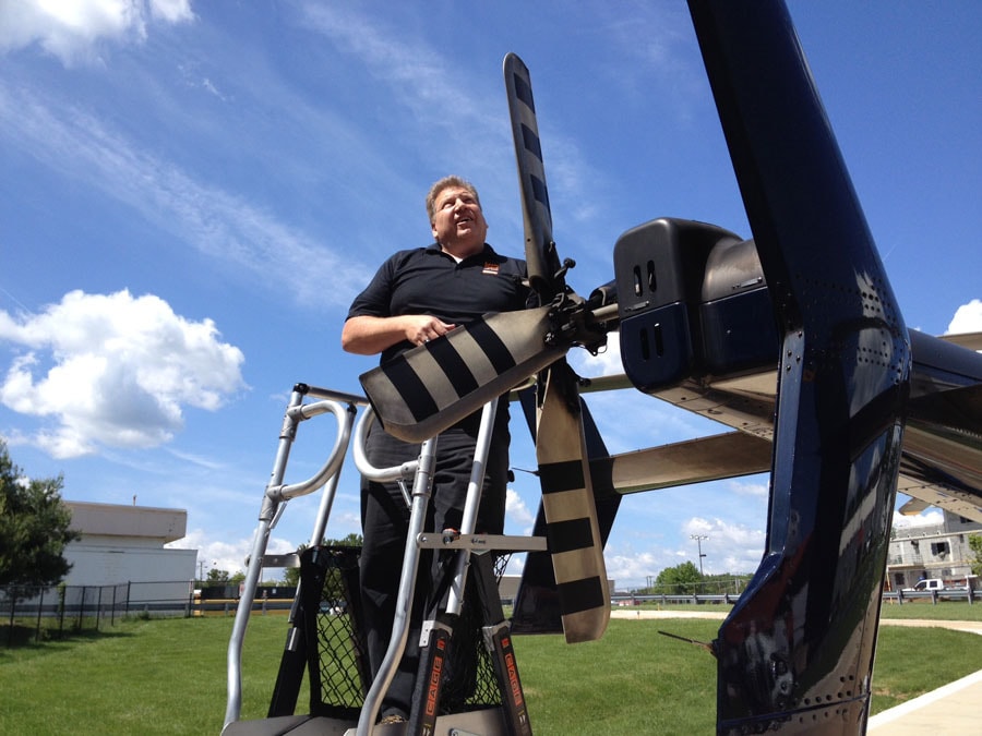 Technician on Little Giant ladder inspecting aircraft propeller